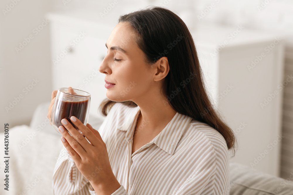 Beautiful young woman with glass cup of hot cocoa in living room Beautiful young woman with glass cup of hot cocoa in living room