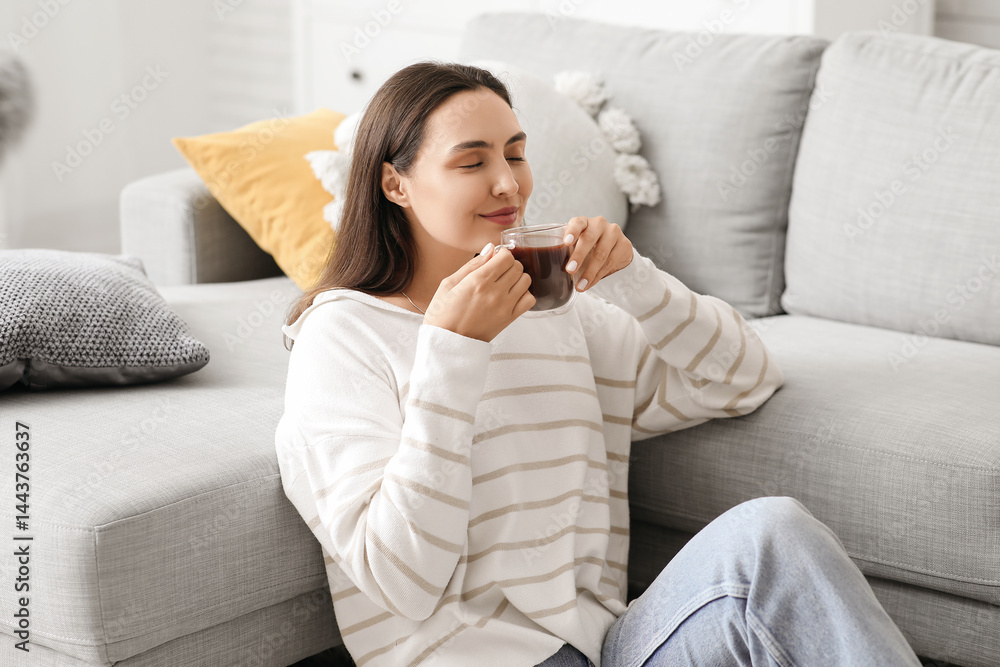 Beautiful young woman with glass cup of hot cocoa in living room Beautiful young woman with glass cup of hot cocoa in living room