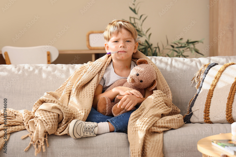 Little boy ill with chickenpox and toy bear measuring temperature on sofa at home Little boy ill with chickenpox and toy bear measuring temperature on sofa at home