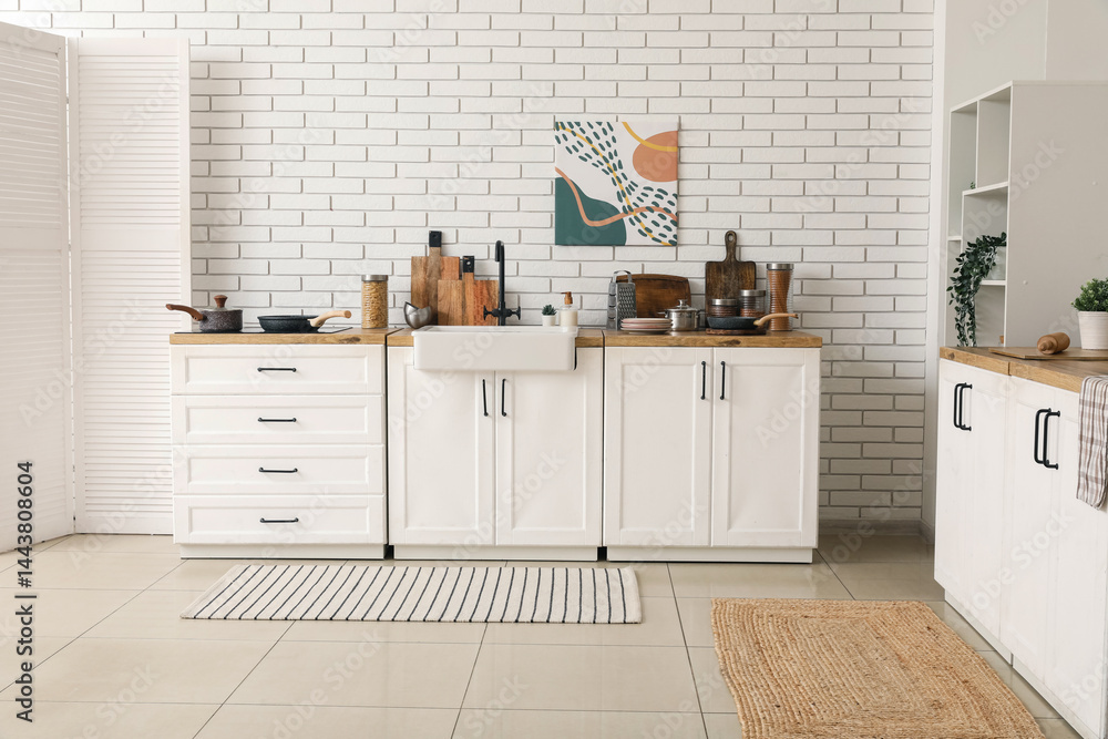 Kitchen counter and folding screen near white brick wall in interior of kitchen
