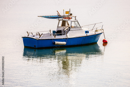 Blue fishing boat moored on calm water