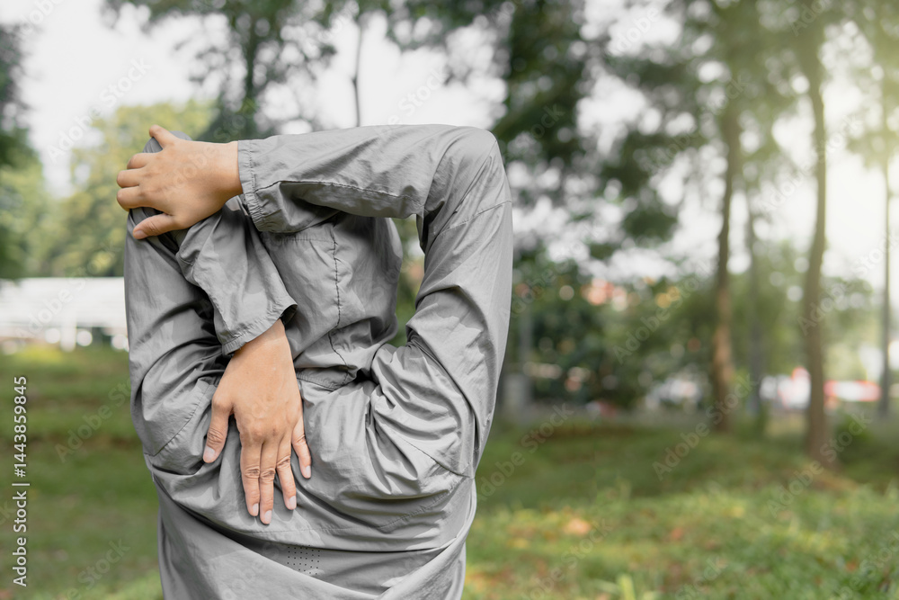 Fototapeta premium Southeast Asian hijabi woman stretching outdoors in park