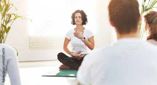 Фотография Yoga instructor training people in a fitness class in studio