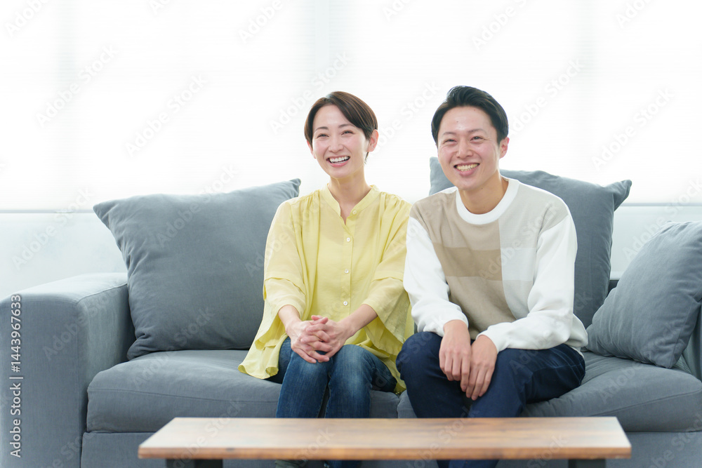 リビングでテレビを見る若い夫婦
