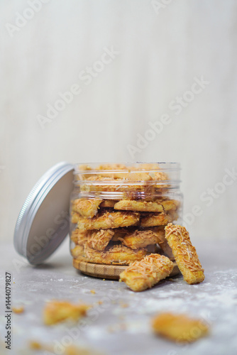 an open jar filled with cheese cookies and some cookies outside with cookie crumbs