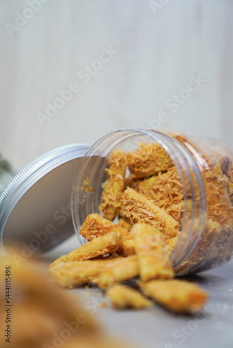 an open jar filled with cheese cookies that was lying down and the cookies came out partially