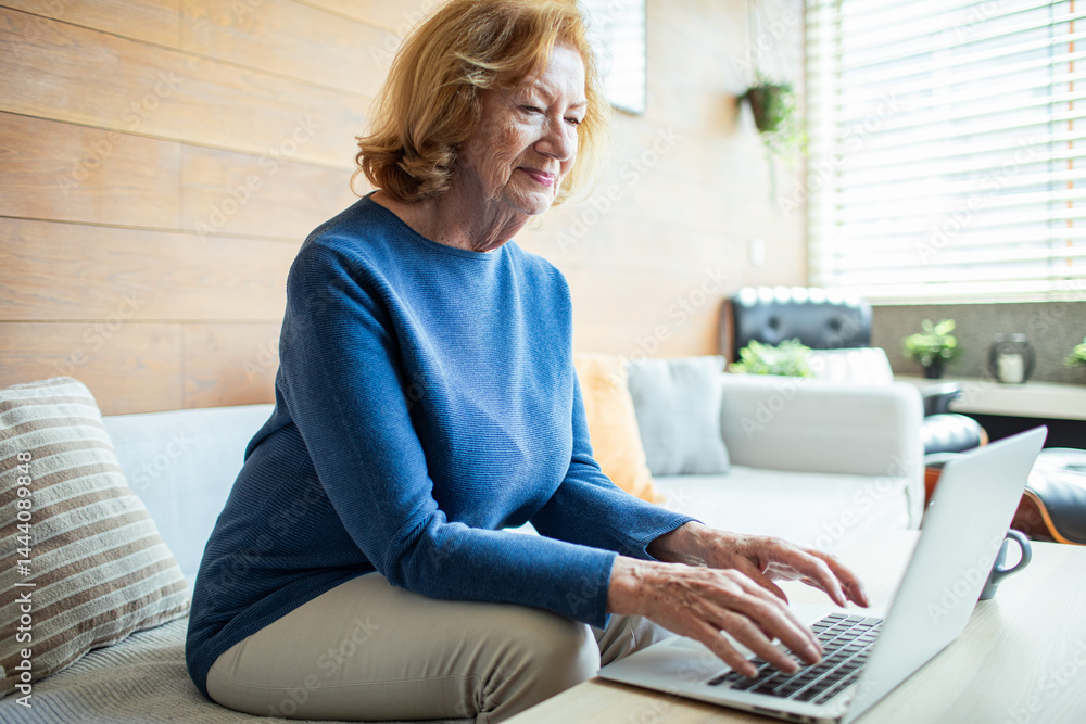 Senior woman typing on laptop in modern home