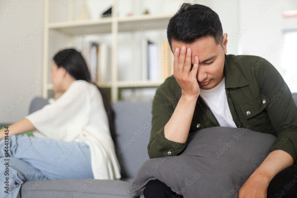 Sad Asian man sitting with hand on head after quarrel with girlfriend at home. Sad Asian man sitting with hand on head after quarrel with girlfriend at home.