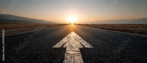 Obraz na płótnie Sunrise over a deserted road, leading towards the horizon with an arrow symbolizing direction and possibilities. w salonie