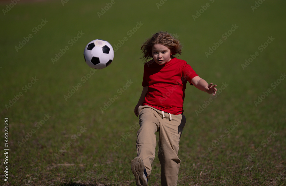 A kid is playing football. A child kicks the soccer ball. Kids sport. Kid football player runs toward goal. Kid kicking football ball. A sporty child enjoys the football. Kids are playing foot ball.