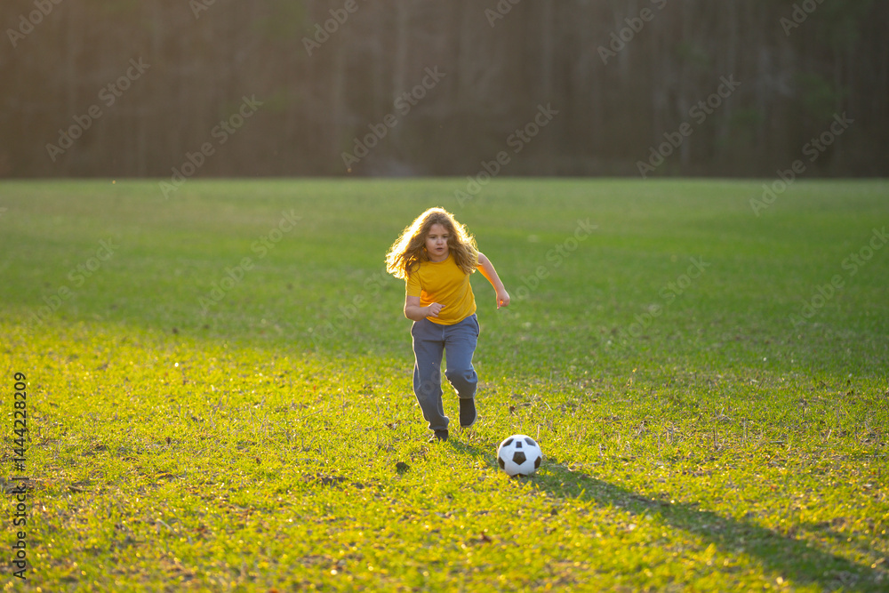 Child playing soccer. Kid boy kicking a football on the grass. Kid running with a soccer ball. Playful children enjoying a football game. Kids soccer match. Kid playing soccer kicking a ball.