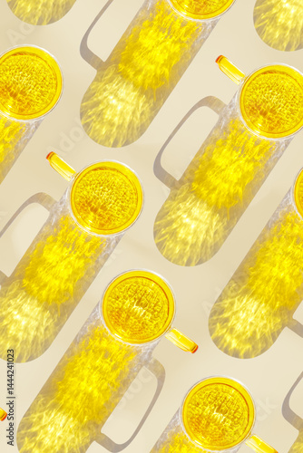 Obraz na płótnie Vibrant yellow glass cups on beige background, casting artistic light reflections and shadows in natural sunlight. Summer drink concept, minimal trend pattern of transparent glasses, monochrome w salonie