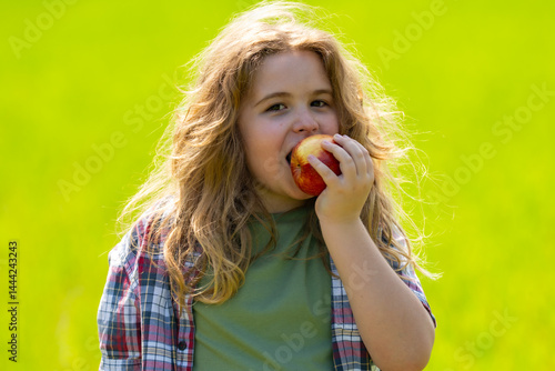 The child boy eats an apple. Ripe fruit for kids. Child bites apple. The child boy eat healthy food. A kid holds apple. Summer sun. Child takes bite of apple. Fresh apples for kids healthy snack.