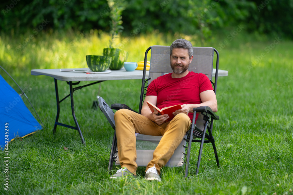 Man enjoying camping in nature. Summer trip on nature. Tourist relaxing in forest camp. Camping trip. Resting near tent after hiking. Freedom vacation in a peaceful campsite. Man on Picnic in summer.