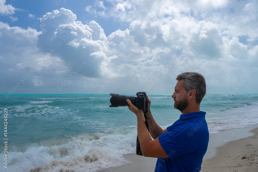 Photographer on beach. Man photographer with a camera on vacation. Traveler photographer by the ocean. Tropical travel photography. Photograph by sea. Photographer on tropical ocean.