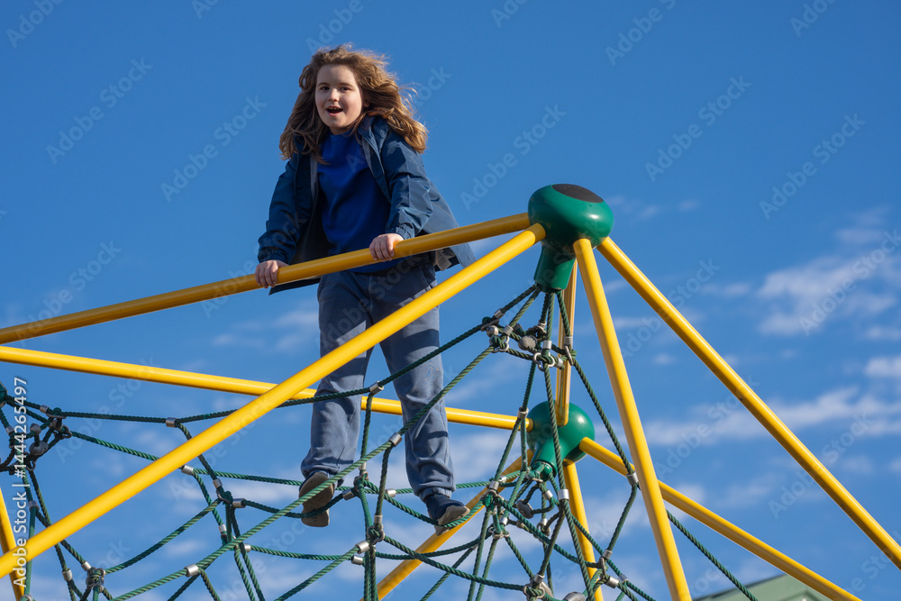 Child climbing outdoors. Active kid climbing at the playground. Child climbing in the park. Happy boy enjoying outdoor play. Cute child having fun on playground. Teen climbing on playground.