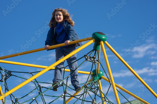 Obraz na płótnie Child climbing outdoors. Active kid climbing at the playground. Child climbing in the park. Happy boy enjoying outdoor play. Cute child having fun on playground. Teen climbing on playground. w salonie