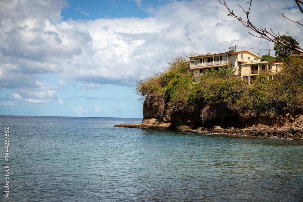 Coastal house perched on a cliff overlooking the ocean under a partly cloudy sky. Coastal house perched on a cliff overlooking the ocean under a partly cloudy sky.