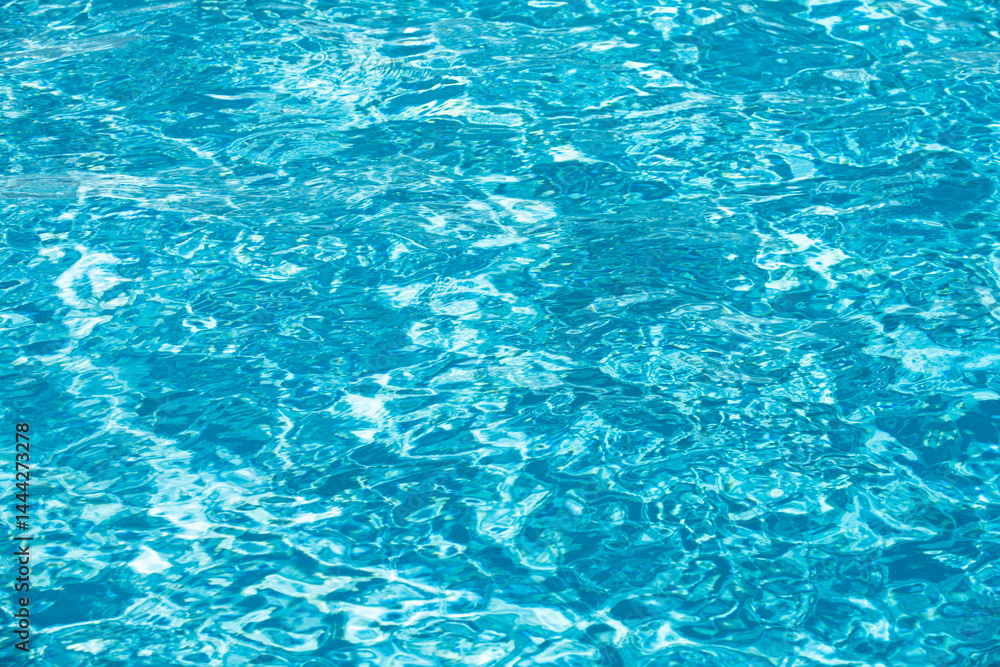 Water background. Blue water, ripples and highlights. Texture of water surface and tiled bottom.