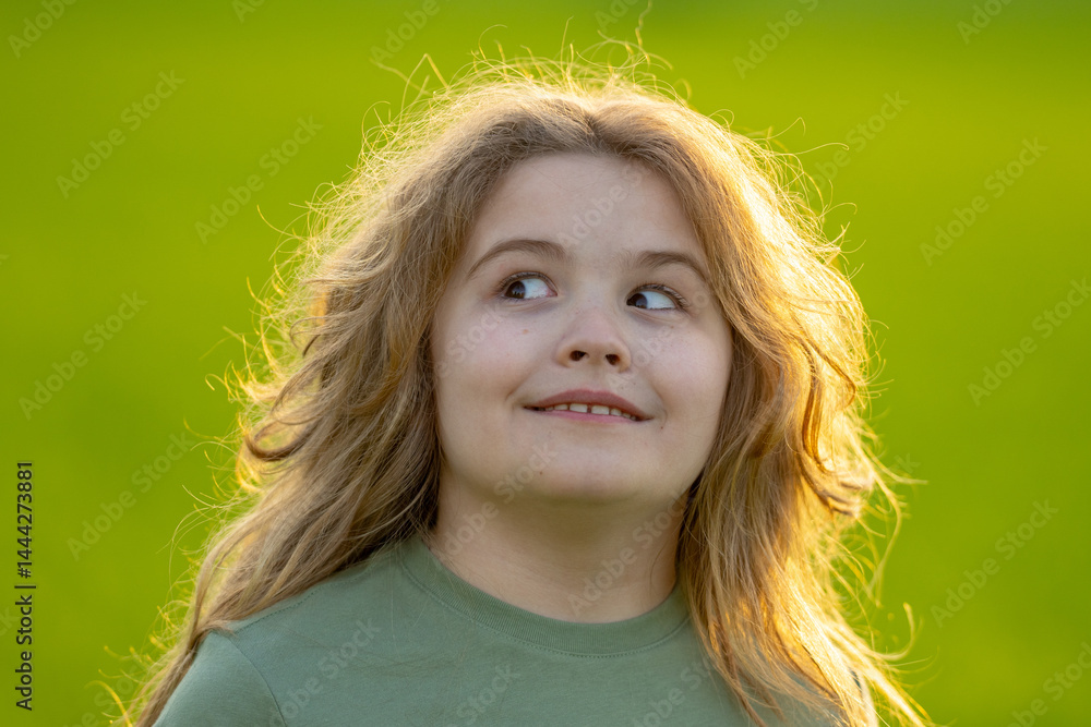 Close-up portrait of kid looks away. Kids face. Summer portrait of happy child looks away. Child face looks away in park. Cute face of cheerful kid outdoors. Fun face of child looks away.