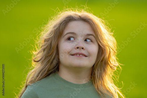 Obraz na płótnie Close-up portrait of kid looks away. Kids face. Summer portrait of happy child looks away. Child face looks away in park. Cute face of cheerful kid outdoors. Fun face of child looks away. w salonie