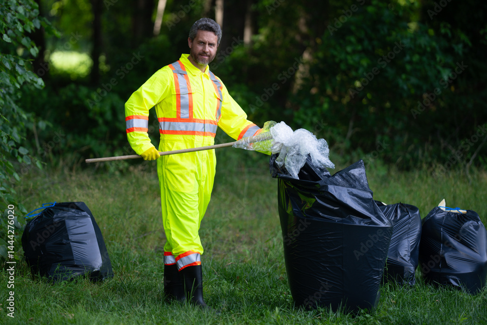 Global environmental pollution. A volunteer collects plastic trash outdoor. The concept of environmental conservation. Man putting household waste into bin bag. Eco volunteer. Pollution environmental.