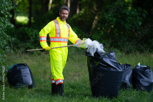 Obraz na płótnie Global environmental pollution. A volunteer collects plastic trash outdoor. The concept of environmental conservation. Man putting household waste into bin bag. Eco volunteer. Pollution environmental. w salonie