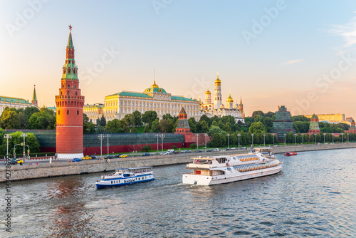View of Kremlin with Vodovzvodnaya tower, Grand Kremlin Palace from repaired Bolshoy Kamenny Bridge in Moscow city on sunny summer day. Cruise ship sails on the Moscow river