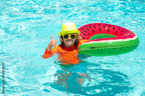 Obraz na płótnie Summer kids vacation, boy swim in pool. Kid in swimming pool, relax swim on inflatable ring and has fun in water on summer vacation. w salonie
