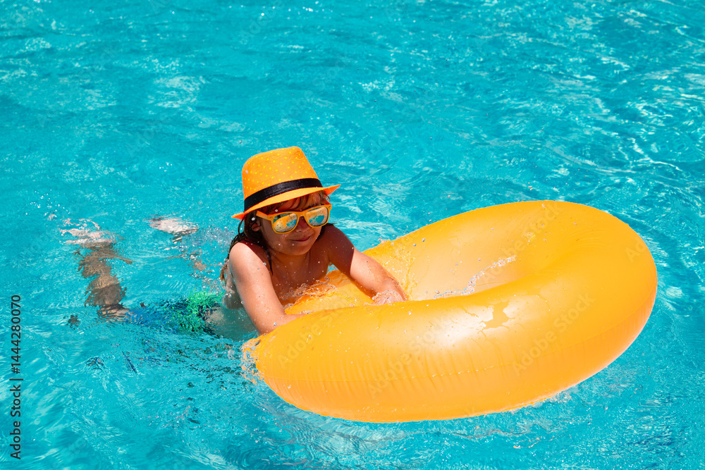Kid swim with floating ring in swimming pool. Kids summer vacation. Happy child boy with inflatable ring in poolside.