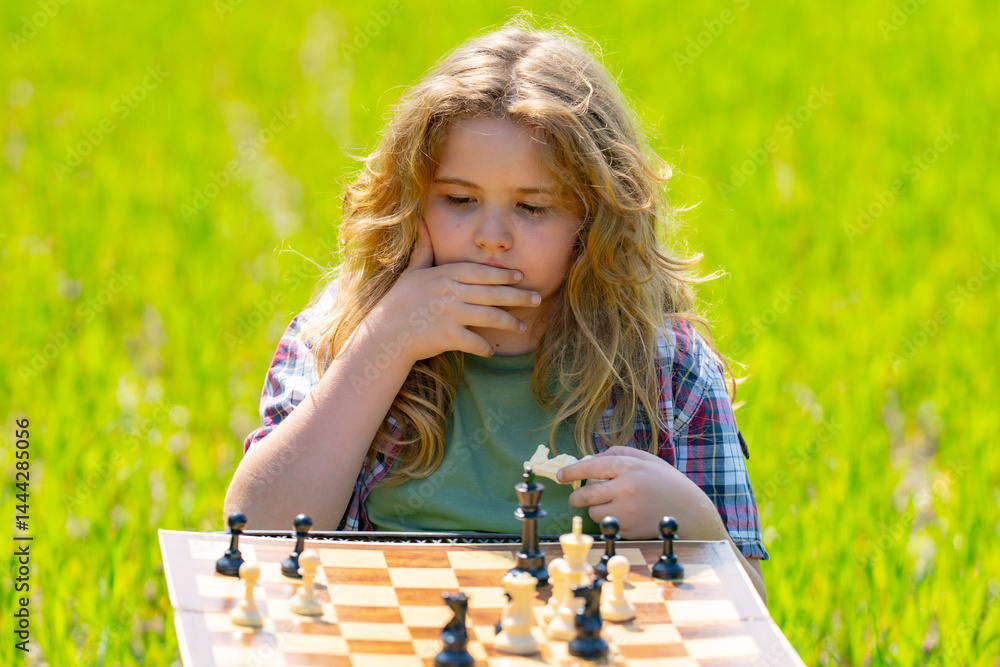 Kid plays chess. A child thinks and playing chess. Kid focuses on chessboard. The child make checkmate. A smart kid plans chess. Child enjoys chess outdoor. Board logic game for child.