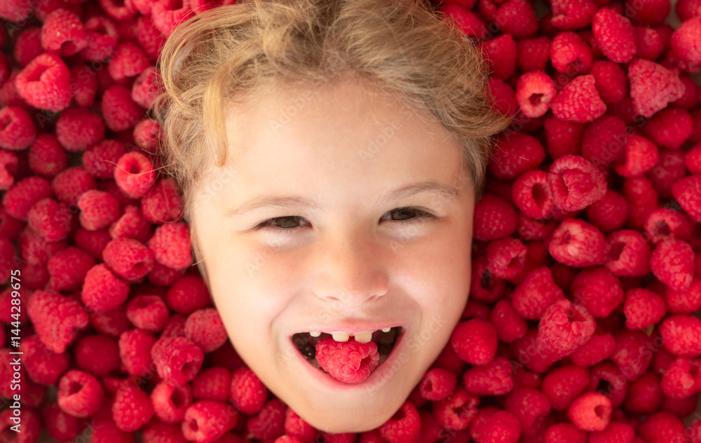 The kids face with raspberries fruit and berries. Summer, pink red raspberry background.
