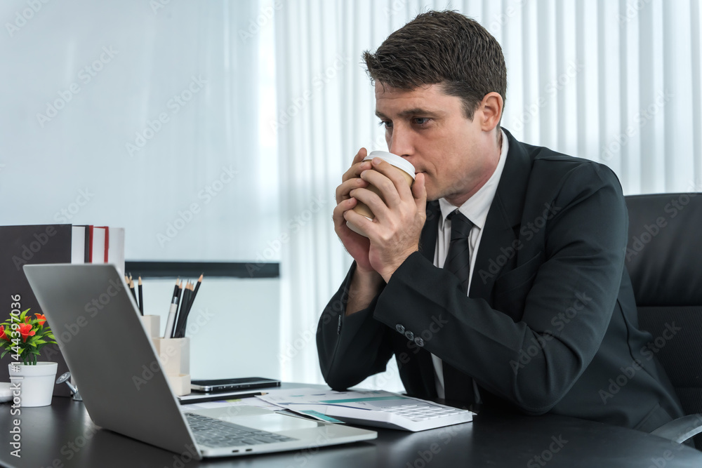 Portrait handsome male Caucasian businessman in suit drinking coffee working in office Portrait handsome male Caucasian businessman in suit drinking coffee working in office