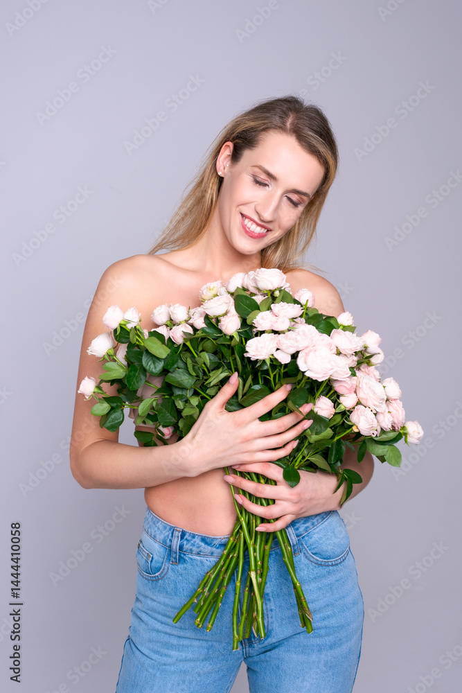A charming woman with a bouquet of pink flowers in her hands in a bright studio creates a romantic atmosphere for advertising floristry and gifts.