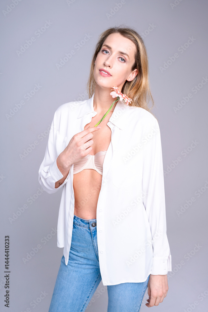 Young woman in jeans and white shirt in relaxed studio photo shoot demonstrates comfortable, natural casual style for clothing advertising