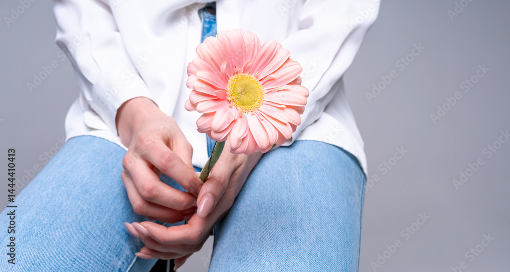 Young woman with pink flower on bright studio background, ideal for beauty, style and naturalness concepts