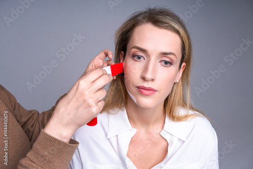 Obraz na płótnie woman with tapes on her face and hands specialist measuring face contour for cosmetic procedures, skin care and aesthetic correction concept, light background. w salonie