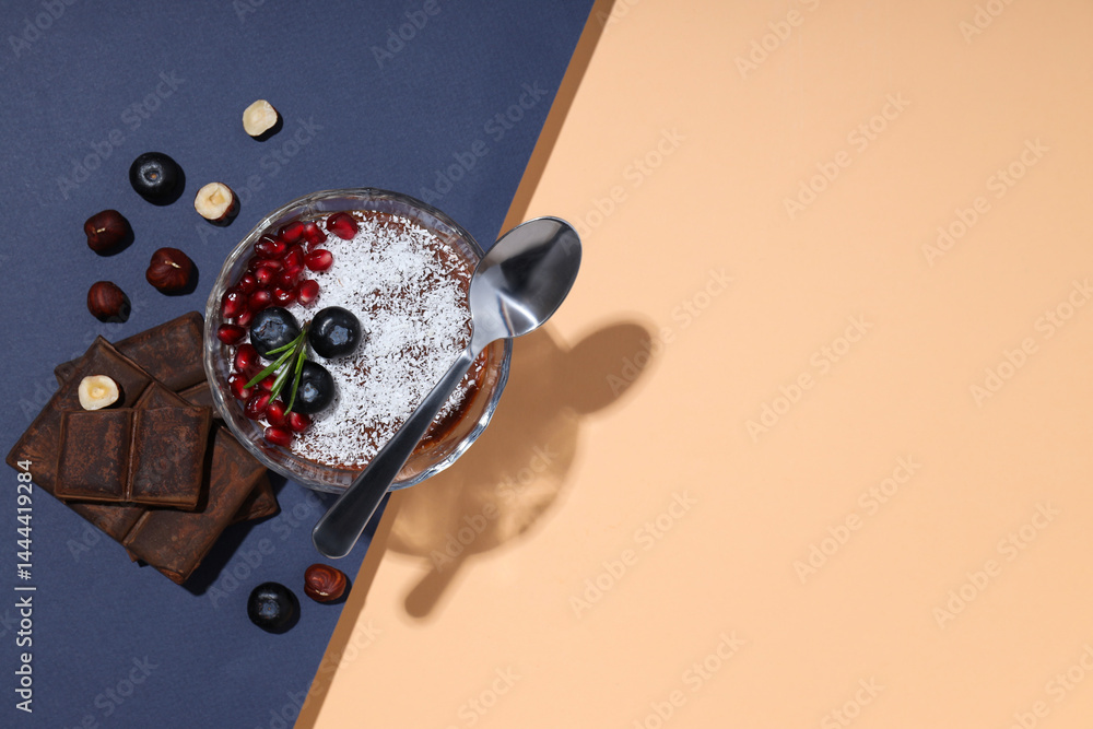 Chocolate mousse with blueberries and pomegranate, on a peach background.