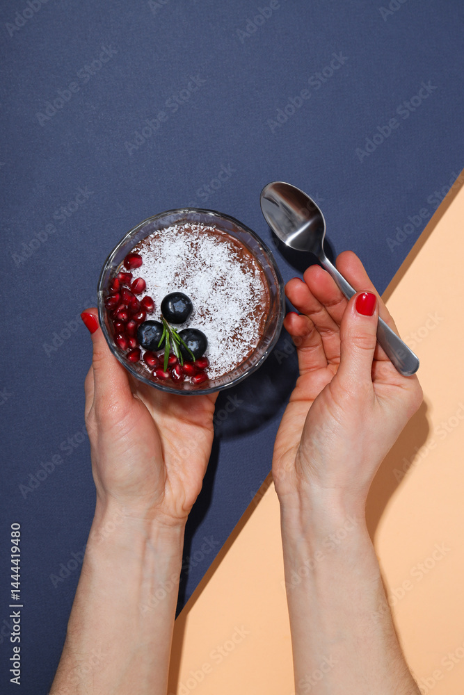 Chocolate mousse with blueberries and pomegranate, on a peach background.