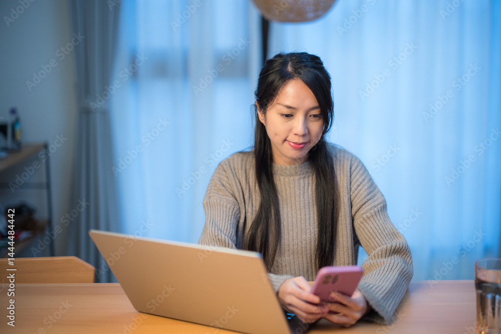 Woman using laptop and phone at night home Woman using laptop and phone at night home