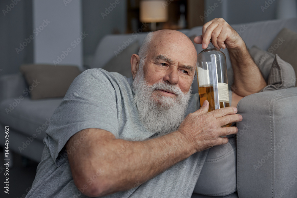 Retired senior man drinking alcohol alone sitting on floor at home