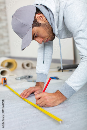 Obraz na płótnie a young man holds a level for measuring floor w salonie