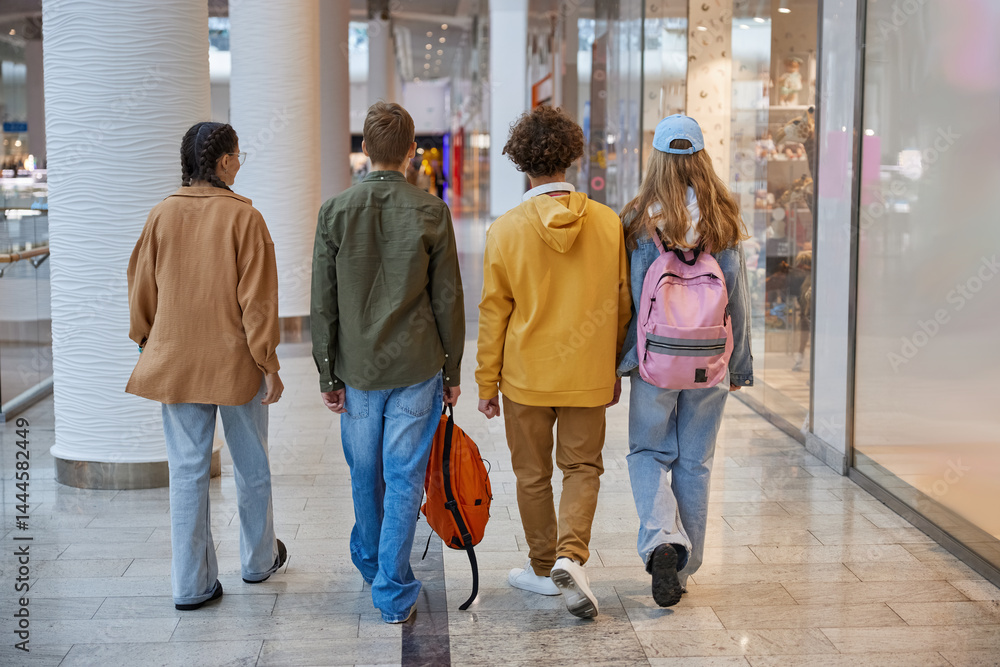 Group of teenagers fooling around running through shopping mall corridor