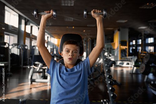 Obraz na płótnie Teen boy lifting dumbbells enjoying sportive workout at gym w salonie