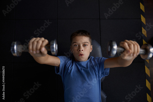 Overhead view portrait of teenage boy training with dumbbells