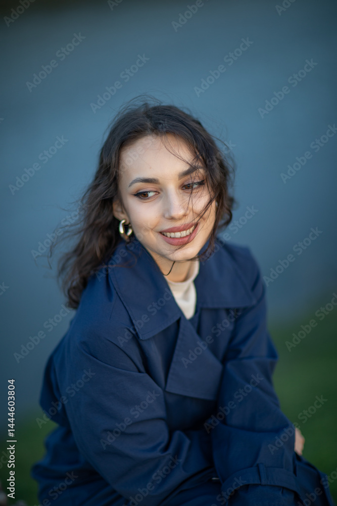 beautiful brunette european girl in blue trench coat at nature. Young lady with beautiful face.
