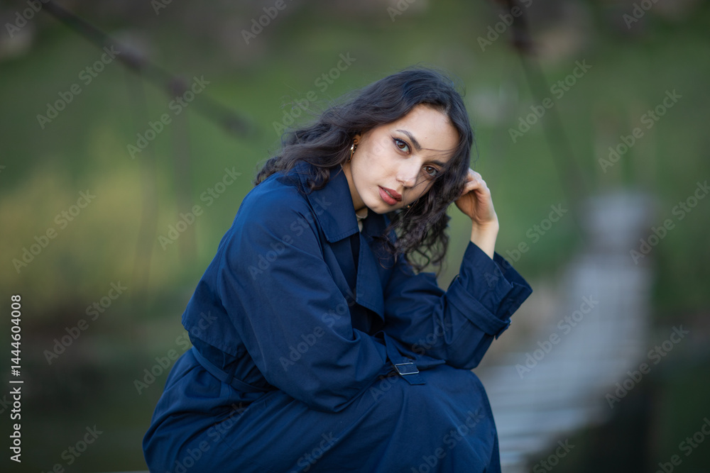 beautiful brunette european girl in blue trench coat at nature. Young lady with beautiful face.