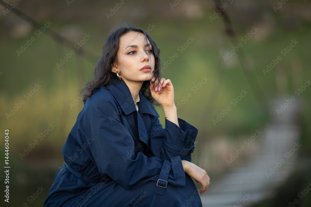 beautiful brunette european girl in blue trench coat at nature. Young lady with beautiful face.