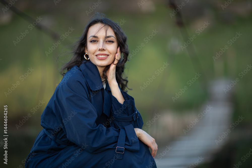 beautiful brunette european girl in blue trench coat at nature. Young lady with beautiful face.