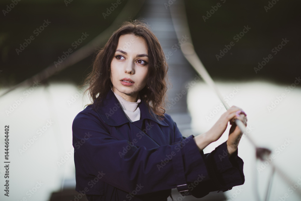 beautiful brunette european girl in blue trench coat at nature. Young lady with beautiful face.